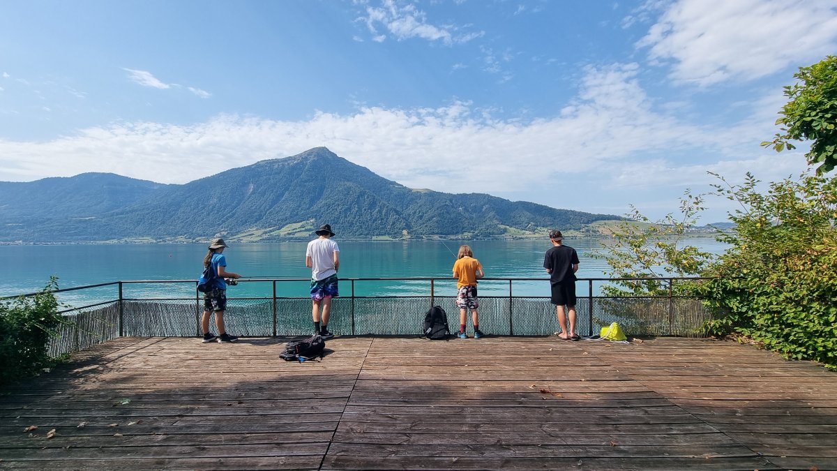Kids fishing group standing on the lakeside platform at Lake Zug